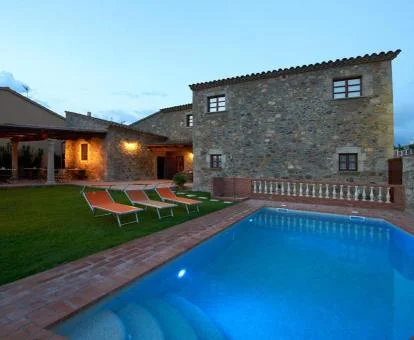 Acogedor hotel rural con fachada de piedra y piscina exterior con tumbonas y jardín.