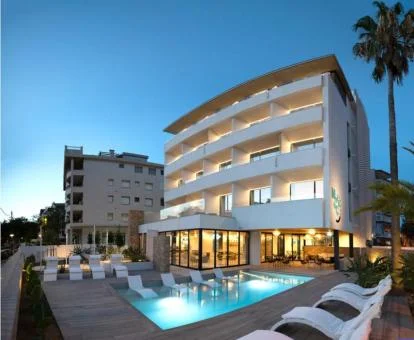 Precioso hotel con piscina exterior y tumbonas.