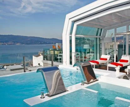 Piscina cubierta con hidroterapia en el exterior con vistas al mar.