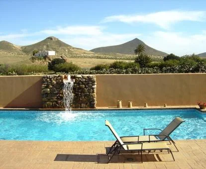 Piscina exterior con chorro de cascada de este hotel rodeado de naturaleza.