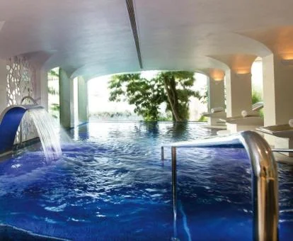 Piscina cubierta con grandes ventanales e hidroterapia del spa del hotel.