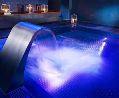 Piscina de hidroterapia en funcionamiento y con iluminación nocturna del spa del alojamiento.