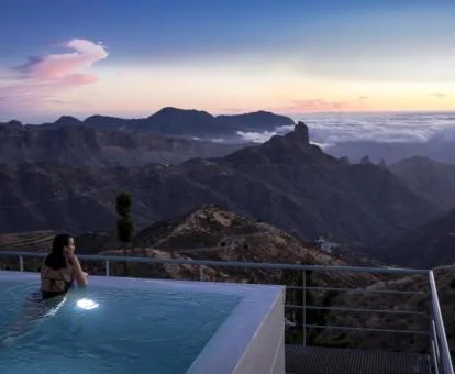 Mujer disfrutando de la piscina exterior de este parador con espectaculares vistas al paisaje.