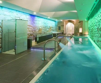 Acogedor spa con piscina cubierta con elementos de hidroterapia y paredes de estilo rústico.