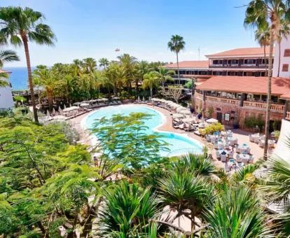 Precioso hotel con piscina rodeada de jardines tropicales.
