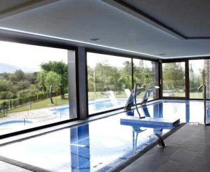 Preciosa piscina cubierta con hidroterapia y vistas a la naturaleza del spa.