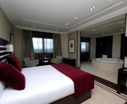 Una suite elegante con cama grande, zona de estar y jacuzzi privado cerca de la cama.