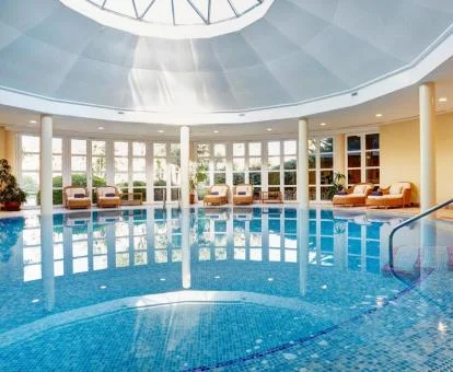 Gran piscina cubierta con zona de relajación y vistas al exterior del spa.
