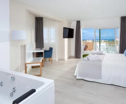 Preciosa suite para dos adultos con bañera de hidromasaje privada cerca de la cama.