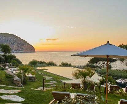 Zona exterior ajardinada con solarium, piscina y vistas al mar de este maravilloso hotel.