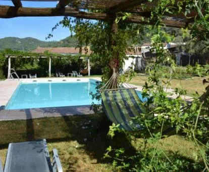 Zona exterior con piscina rodeada de vegetación y bellos jardines de este alojamiento rural.