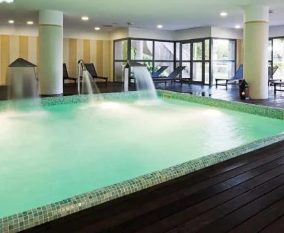 Piscina cubierta con hidroterapia y vistas al exterior del centro de bienestar del hotel.