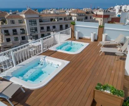 Terraza solarium con bañera de hidromasajes exteriores y vistas a la ciudad de este hotel.