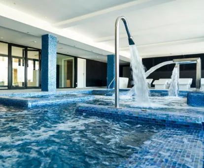 Piscina cubierta con elementos de hidroterapia en funcionamiento del spa del hotel.