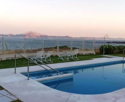 Piscina exterior con solarium y vistas al mar de este hotel.