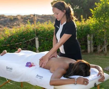 Mujer disfrutando de un masaje al aire libre en los jardines del hotel.