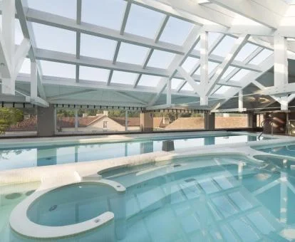 Piscina cubierta con elementos de hidroterapia y vistas al exterior de la piscina.