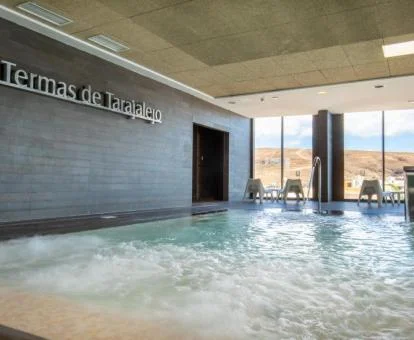 Piscina cubierta con hidroterapia y vistas al exterior del centro de bienestar del hotel.