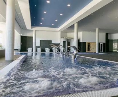 Piscina cubierta con hidroterapia y zona de relajación del spa.
