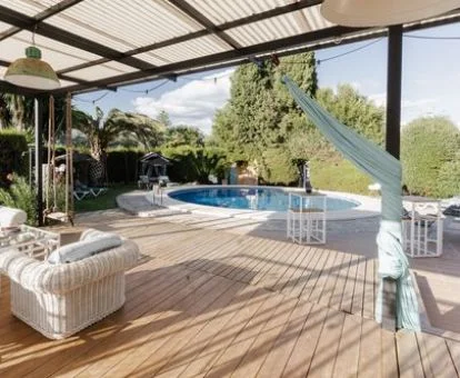 Terraza con piscina y mobiliario rodeada de vegetación de este alojamiento rural.