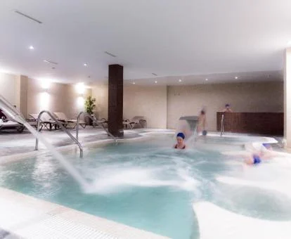 Mujer disfrutando de la piscina cubierta con hidroterapia del spa.