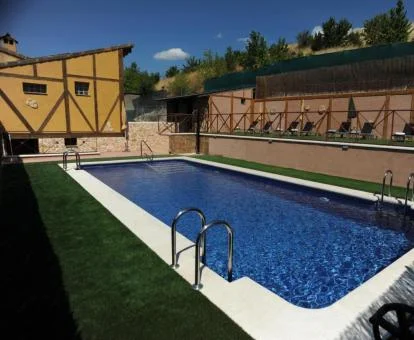 Hotel rural con piscina exterior y solarium con tumbonas.