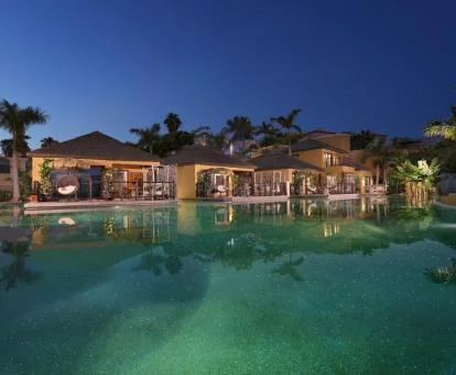 Fabuloso hotel solo para adultos con una amplia piscina e iluminación nocturna.