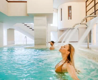 Pareja disfrutando de la piscina con elementos de hidroterapia del hotel.