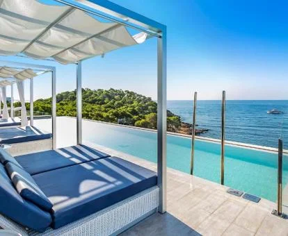 Preciosa piscina de borde infinito con camas y fabulosas vistas.