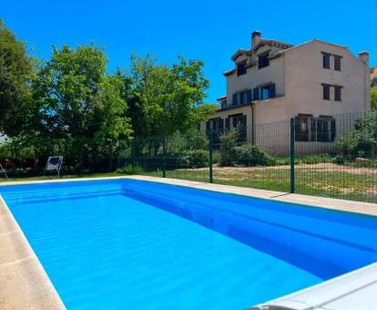 Hotel rural rodeado de jardines y vegetación con piscina al aire libre.