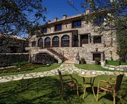 Edificio de piedra de este hotel rural con bellos jardines y mobiliario exterior.