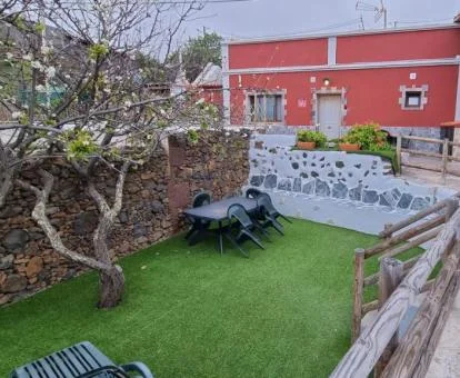 Acogedora casa rural con zona exterior ajardinada y mobiliario al aire libre.