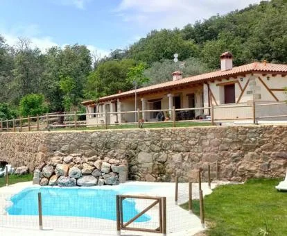 Hermoso hotel rural rodeado de vegetación con piscina al aire libre.