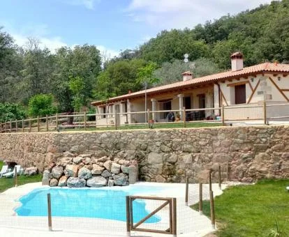 Precioso hotel rural con piscina rodeado de vegetación.