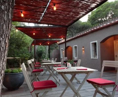 Acogedora terraza de este hotel rural con comedores bajo los árboles e iluminación.