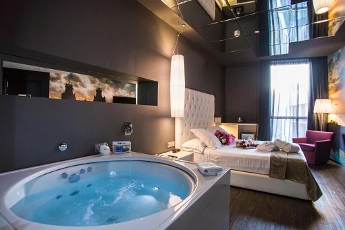 Foto de habitación muy romántica donde tienes el jacuzzi junto a la cama y un espejo en el techo.