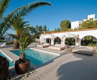 Zona exterior con piscinas y palmeras de este hotel con encanto.