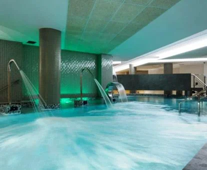 Gran piscina cubierta con elementos de hidroterapia del spa.
