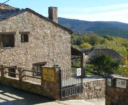 Edificio de piedra de este hotel rural con vistas a las montañas.