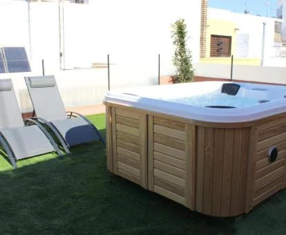 Agradable terraza privada del ático con tumbonas y un gran jacuzzi al aire libre.