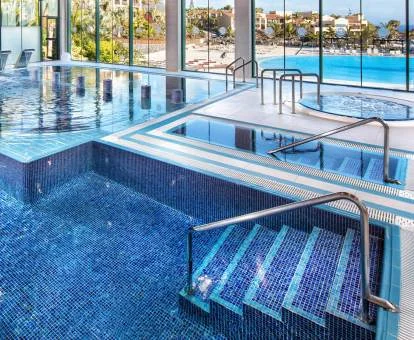 Espectacular piscina con elementos de hidroterapia y vistas al exterior del spa del hotel.