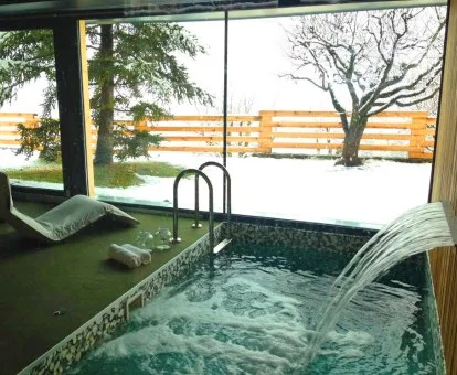 Piscina cubierta con hidroterapia y vistas al jardín nevado del hotel.