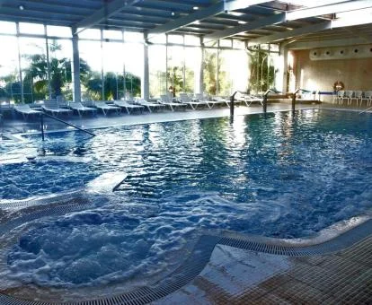 Gran piscina de hidroterapia con vistas al exterior del spa del hotel.