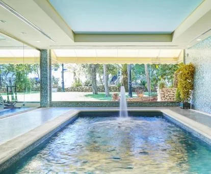 Piscina cubierta con chorros de hidroterapia del spa y vistas al exterior.