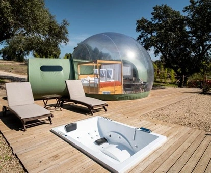 Hotel burbuja en medio del campo con una terraza exterior con mobiliario y con un jacuzzi en el suelo