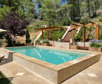 Agradable zona exterior con piscina y mobiliario rodeada de vegetación.