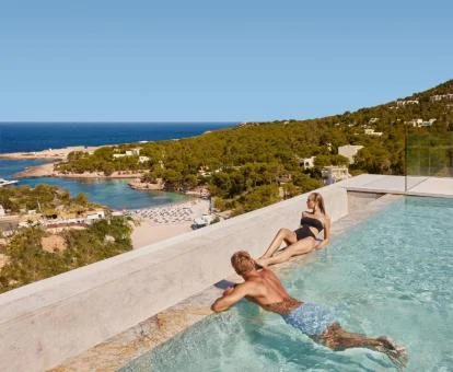 Pareja disfrutando de la piscina con vistas al mar de este hotel con encanto.