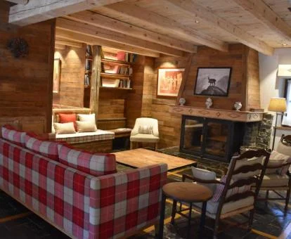 Acogedor salón de uso compartido con chimenea y estilo de montaña de este hotel boutique.