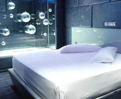 Cama amplia con sábanas blancas de una de las suites con la bañera de hidromasaje privada al lado.