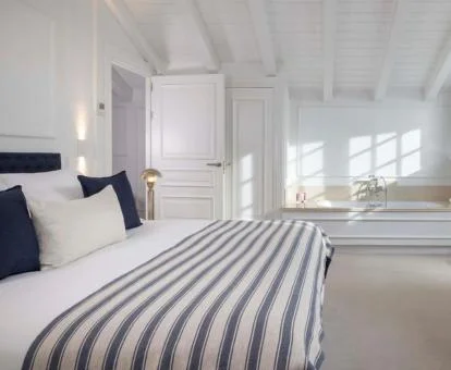Una de las amplias y luminosas habitaciones con bañera cerca de la cama del hotel.